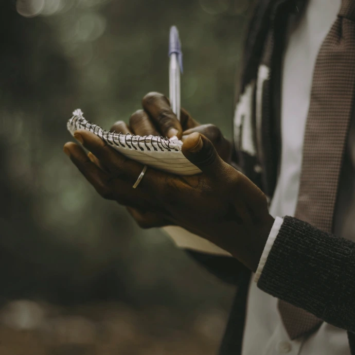 Person writing notes in a notebook outdoors